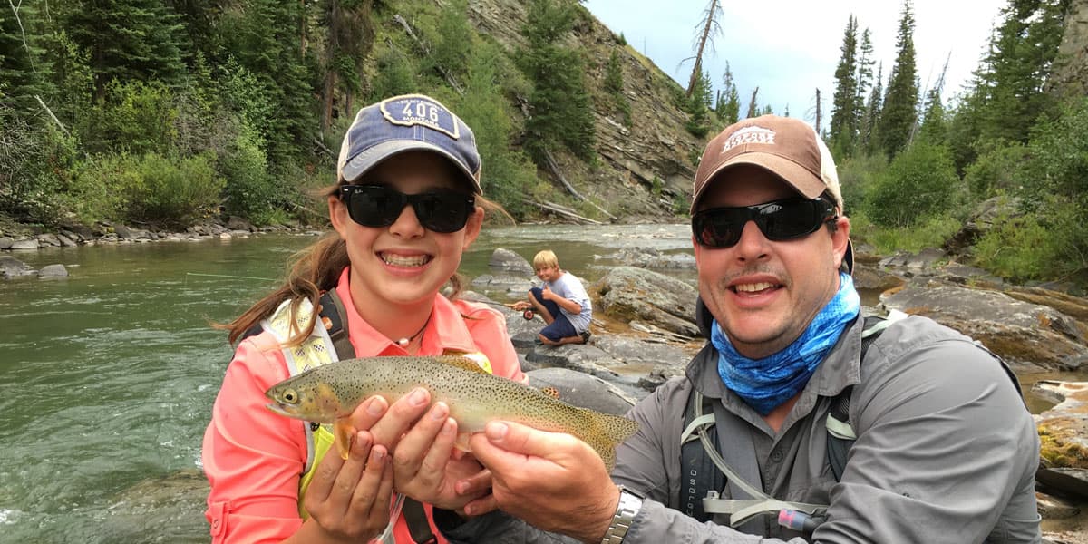 girl holding trout on river bank